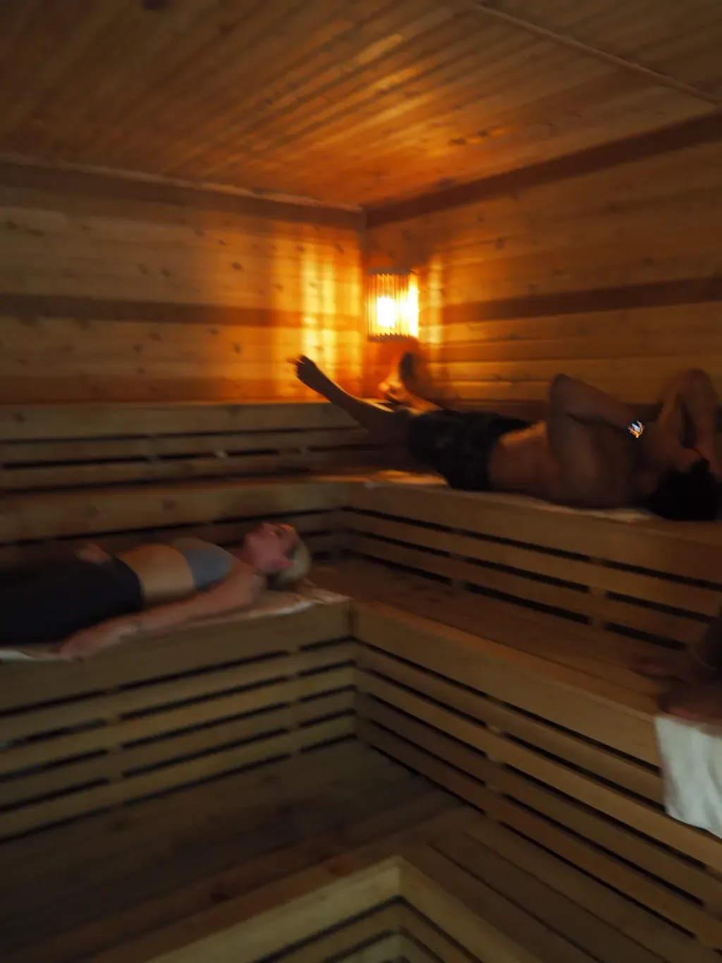 Guest lying back on the upper bench of the Finnish sauna at Sauna Culture Charlotte